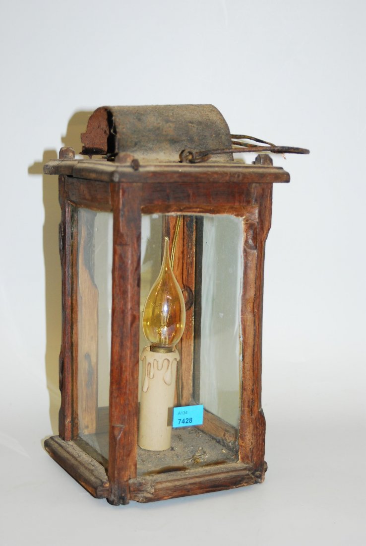 Handlaterne 19.Jh. Quadratisches Holzgehäuse mit: Handlaterne 19.Jh. Quadratisches Holzgehäuse mit Glasfenstern und Drahthenkel. Elektrifiziert. H 30 cm. - Tlw. stark verwittert.