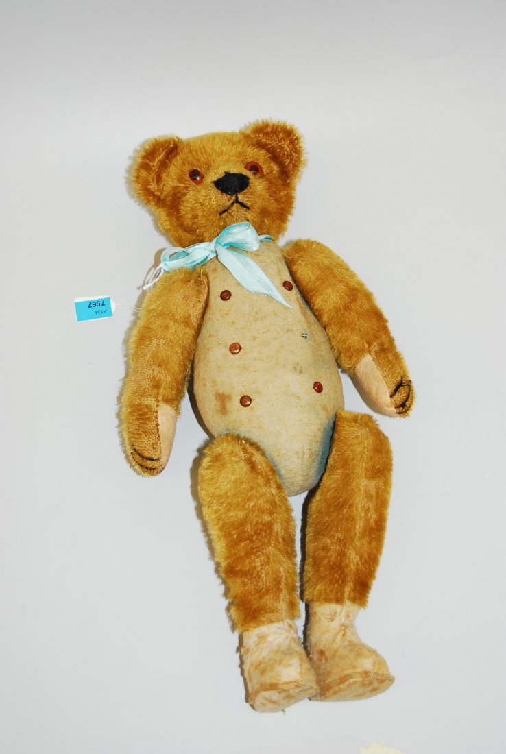 Zweigesichter-Teddybär Um 1900. Honigfarbener: Zweigesichter-Teddybär Um 1900. Honigfarbener Mohairplüsch/Stoff. Drehbarer Kopf aus Celluloid mit zwei Gesichtern: Mädchen-, bzw. Bärengesicht. H 37 cm. - stark abgeliebt, Altersspuren.