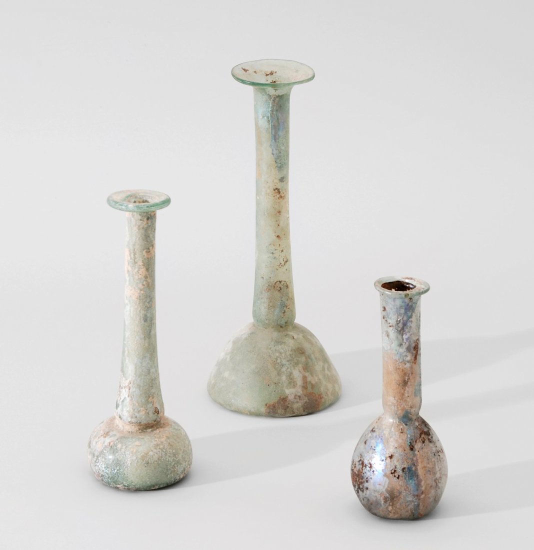 Lot: 2 Unguentari, 1 Balsamarium Östliches: Lot: 2 Unguentari, 1 Balsamarium Östliches Mittelmeergebiet, 1.–2.Jh. n. Chr. Durchsichtiges, bläulich-grünes Glas. Glockenförmig mit langem zylindrischen Hals und breitem Rand. H 14–17,8. Bir