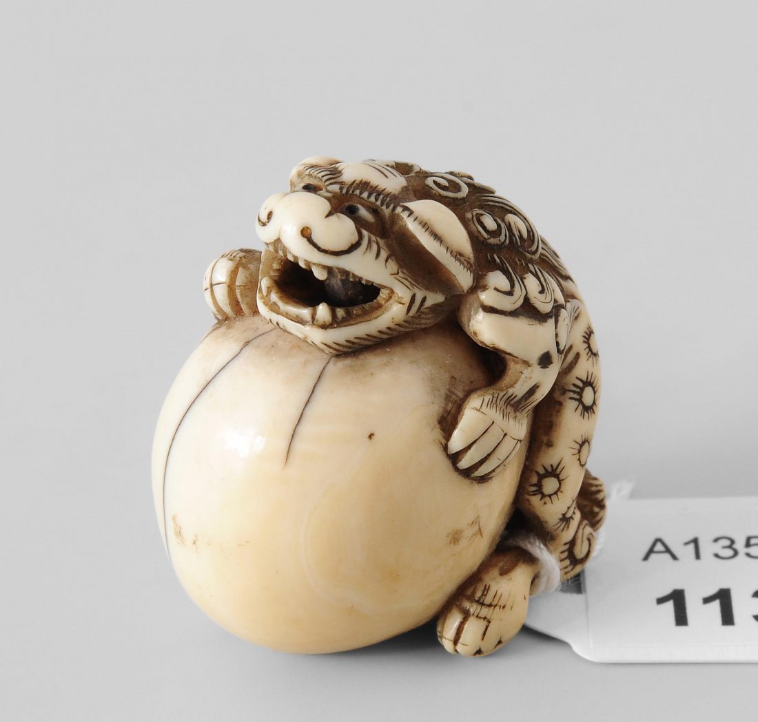 Netsuke Japan, 19.Jh. Elfenbein. Shishi hält eine: Netsuke Japan, 19.Jh. Elfenbein. Shishi hält eine grosse Kugel. Eine kleine bewegliche Kugel befindet sich im Maul. H 3,5 cm.