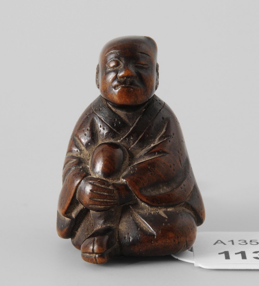 Netsuke Japan, um 1900. Holz, geschnitzt. Signiert: Netsuke Japan, um 1900. Holz, geschnitzt. Signiert Hôzan. Mann mit Beule am Kopf und geschwollenem Gesicht umfasst sein Knie mit beiden Armen. H 4 cm.