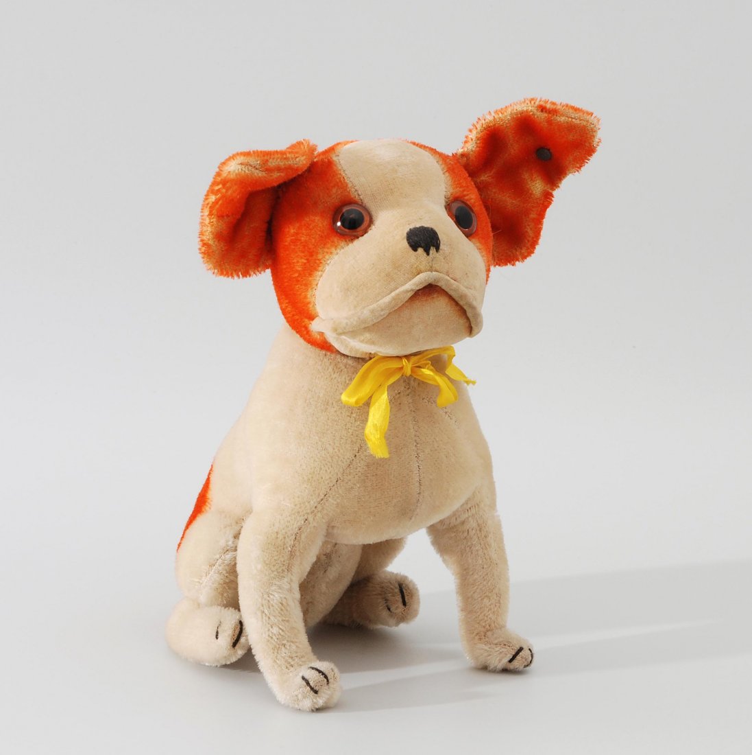 Steiff-Tier "Bully" Deutschland, um 1930. Sitzend.: Steiff-Tier "Bully" Deutschland, um 1930. Sitzend. Heller Mohairplüsch, weiss/braun, Gesicht aus Samt. Drehbarer Kopf. Nase und Krallen gestickt. Braune Glasaugen. Ohne Halsband. Mit Knopf. H 22 cm. 