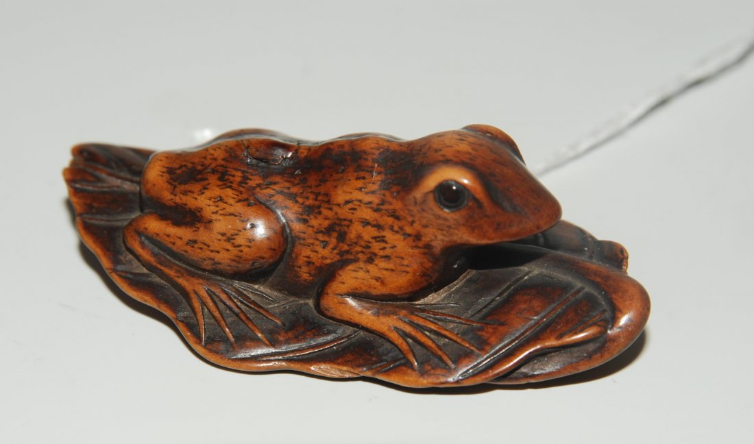 Netsuke Japan, um 1900. Holz. Frosch, bäuchlings: Netsuke Japan, um 1900. Holz. Frosch, bäuchlings lauernd auf einem Blatt, mit wachen, aufmerksamen Augen. L 5,6 cm.
