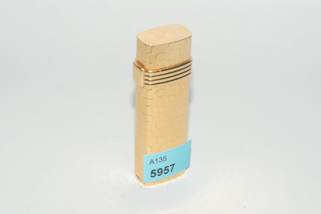 Christian Dior, Feuerzeug Vergoldet. Guillochiert. Mit: Christian Dior, Feuerzeug Vergoldet. Guillochiert. Mit Initalen des Designers "CD" und dekorativem vierreihigem Band an der Öffnung verziert. Gas. L 7 cm. Wenige Gebrauchsspuren.