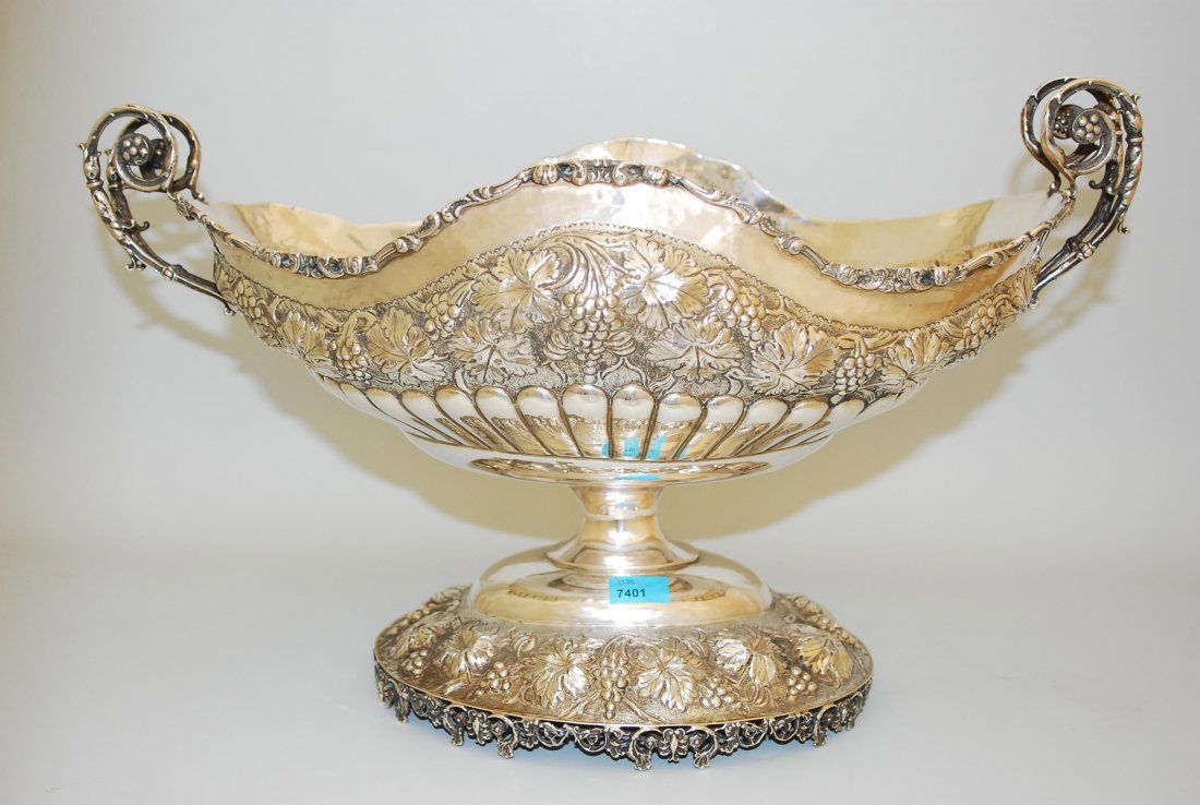 Grosse Aufsatzschale 20.Jh. Silber/Metall versilbert.: Grosse Aufsatzschale 20.Jh. Silber/Metall versilbert. Ovalform. Auf getrepptem Stand gemuldete ovale Schale mit zwei Volutenhenkel an den Schmalseiten. Reicher, reliefierter Weinrebendekor. 44x20x27 c