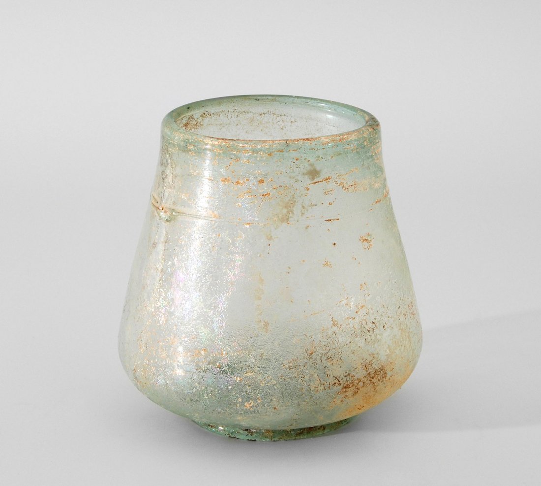 Becher Östlicher Mittelmeerraum, vermutlich 2.–3.Jh. n.: Becher Östlicher Mittelmeerraum, vermutlich 2.–3.Jh. n. Chr. Leicht bläulich-grünes Glas. Konisch. Angesetzter Standring. Verdickter Rand. Unter dem Rand Fadenauflage. Verwittert, leicht irisiere