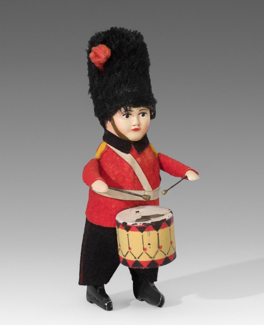 Schuco-Tanzfigur "Englischer Guard als Trommler": Schuco-Tanzfigur "Englischer Guard als Trommler" Deutschland, 1930er Jahre. Metallkörper mit Plüschkopf und bunter Filzbekleidung, hohe Bärenmütze aus Plüsch. Fussprägung "SCHUCO PATENT" bzw. "M
