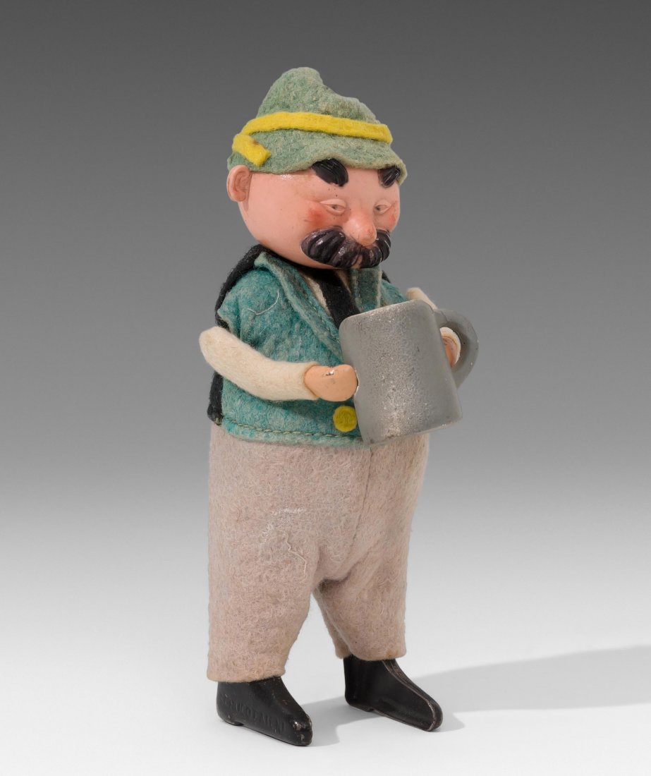 Schuco-Tanzfigur "Trachtenfigur mit Bierkrug": Schuco-Tanzfigur "Trachtenfigur mit Bierkrug" Deutschland, 1930er Jahre. Metallkörper mit Kopf aus Celluloid und bunter Filzbekleidung. Grauer Bierkrug (wohl original) aus Keramik. Fussprägung "SCHU