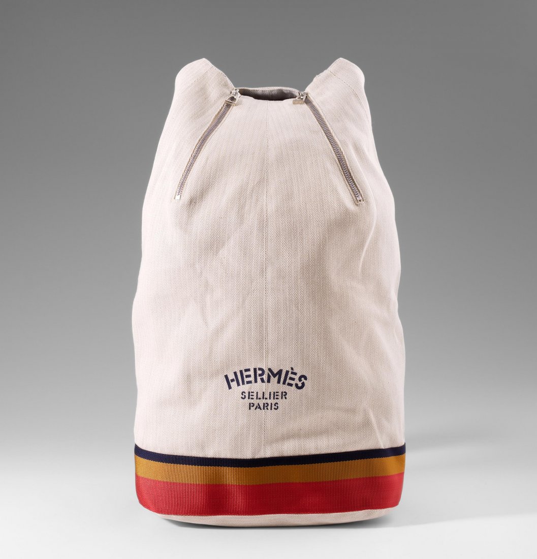 Hermès, "Sac Marin" Matrosentasche aus naturfarbenem: Hermès, "Sac Marin" Matrosentasche aus naturfarbenem Canvas. Diskretes Chevron-Muster. Auf der Voderseite gemarkt "Hermès Sellier Paris". Blau-gelb-roter Schultertrageriemen. Ca. 29x49x19 cm. Sehr g