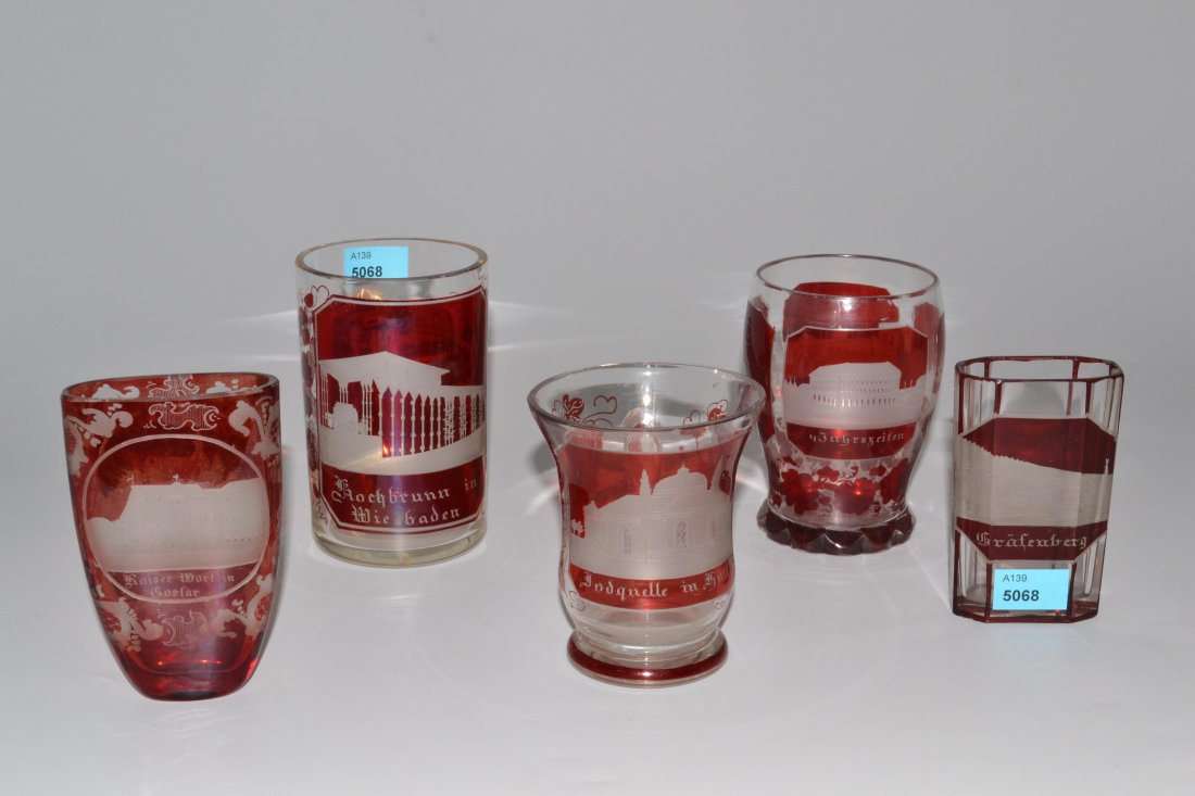 Lot: 5 Ansichtenbecher, Böhmen 19.Jh. Farbloses: Lot: 5 Ansichtenbecher, Böhmen 19.Jh. Farbloses Kristallglas, rot lasiert, Architekturdarstellungen in Mattschnitt mit Inschriften "Kochbrunn in Wiesbaden", "Kaiser Wort in Goslar" bzw. "Frankenb. Ki