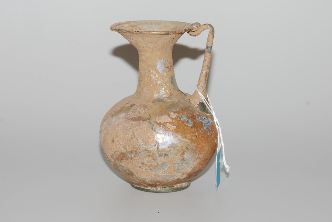Kleiner Krug Östlicher Mittelmeerraum, 2.–3.Jh. n. Chr.: Kleiner Krug Östlicher Mittelmeerraum, 2.–3.Jh. n. Chr. Leicht grünliches, durchschimmerndes Glas. Stark Verkrustet und leicht irisierend. Risse. H 11,5 cm.