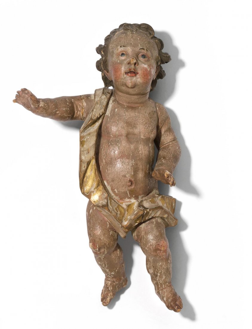 Putto Sddeutsch, 18.Jh. Holz geschnitzt und polychrom: Putto Sddeutsch, 18.Jh. Holz geschnitzt und polychrom gefasst, tlw. vergoldet. Putto mit erhobenem rechtem Arm und Lendentuch. Vollplastisch. H 50 cm. - Kleine Schad- und Fehlstellen. Grosse linke Zeh