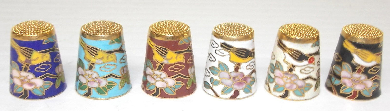 SET OF 6 CHINESE CLOISONNE THIMBLES: SET OF 6 CHINESE CLOISONNE THIMBLES WITH BIRD AND TREE BRANCH MOTIF EACH STAND 1” TALL AND MEASURES 3/4” IN DIAMETER. Note: This item tested positive for traces of gold by U. S. Customs agents. Th