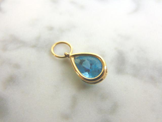 Womens Vintage Estate 18k Yellow Gold Topaz Pendant: A WOMENS VINTAGE ESTATE 18K YELLOW GOLD PENDANT WITH A TOPAZ COLORED STONE. THE PENDANT WEIGHS 1.3g, AND MEASURES 3/4" LONG BY 1/4" WIDE. NOT SURE IF THE TOPAZ STONE IS REAL OR MAN MADE. PENDANT IS NO