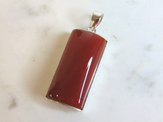Womens Vintage Estate Sterling Silver Carnelian Pendant: FOR SALE IS THIS WOMENS VINTAGE ESTATE STERLING SILVER CARNELIAN COLORED PENDANT . NOT SURE IF STONE IS REAL OR MAN MADE. PENDANT WEIGHS 10.2g AND PENDANT MEASURES 1 5/8" LONG BY 5/8" WIDE. MAKES A GR