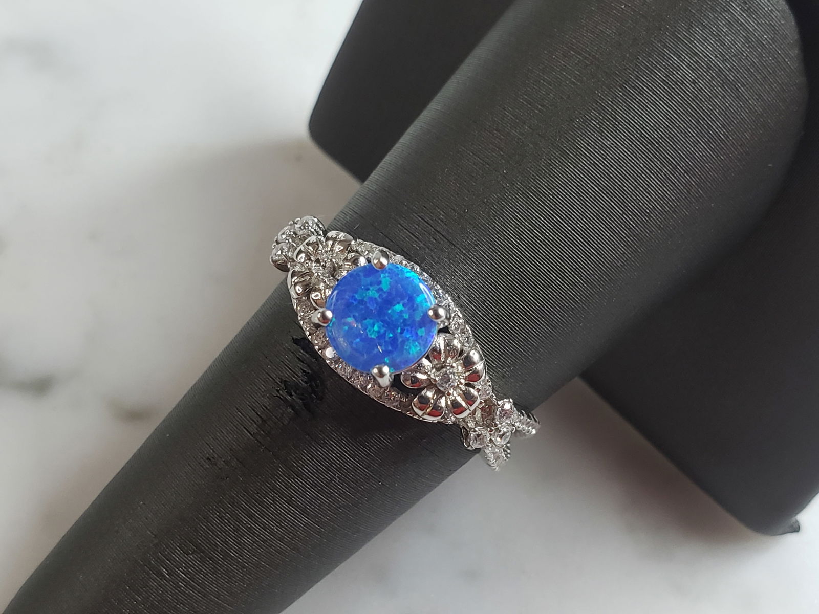 Womens Estate Sterling Silver Modernist Blue Opal Floral Ring: A WOMENS ESTATE STERLING SILVER MODERNIST OPAL COLORED FLORAL RING. THE RING IS A SIZE 7.75 AND WEIGHS 3.2g. WIDTH OF RING MEASURES 3/8". NOT SURE IF STONE IS NATURAL OR MAN MADE. THE RING MAKES A BEA