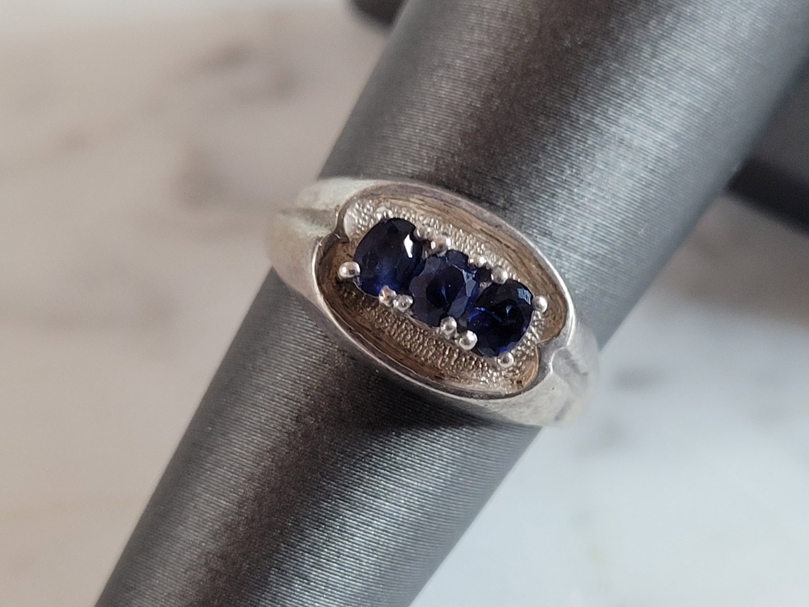 Womens Vintage Estate Sterling Silver Sapphire Ring: A WOMENS VINTAGE ESTATE STERLING SILVER RING WITH SAPPHIRE COLORED STONES. NOT SURE IF THE STONE IS REAL OR NOT. THE RING WEIGHS 4.5g, AND IS A SIZE 6.0. THE WIDTH OF THE RING IS 3/8". ANY QUESTIONS P