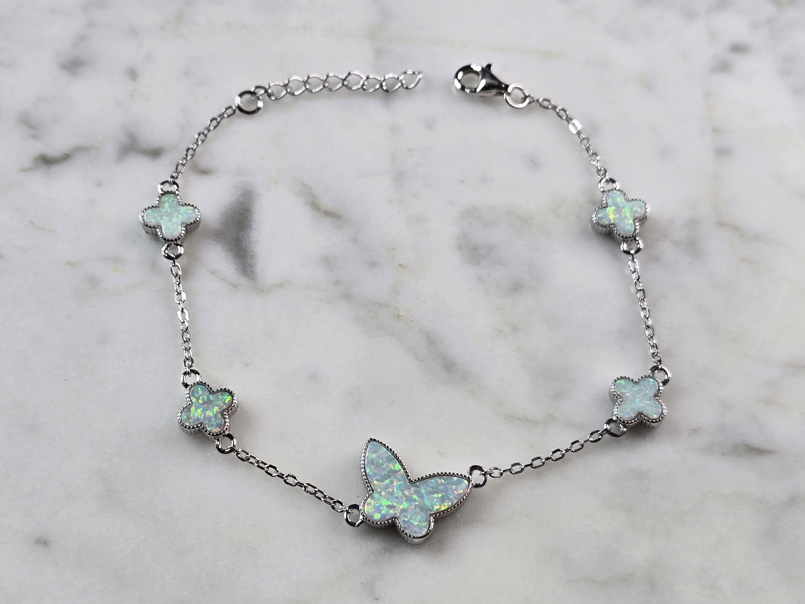 Womens Sterling Silver Opal Butterfly Charm Bracelet: A WOMENS STERLING SILVER MODERNIST OPAL COLORED BUTTERFLY CHARM BRACELET. THE BRACELET WEIGHS 5.3g AND MEASURES 7 3/8" LONG BY 1/2". NOT SURE IF OPAL IS NATURAL OR MAN MADE. ANY QUESTIONS PLEASE DO NO