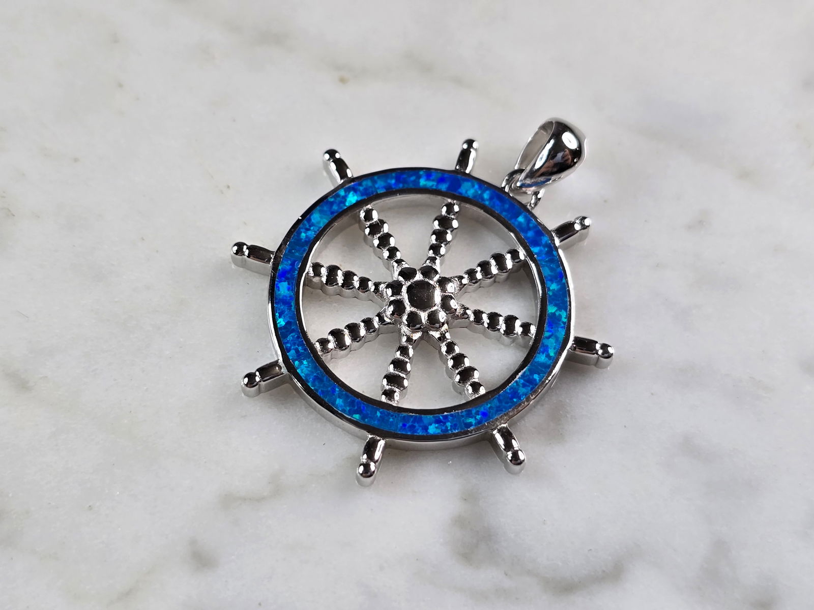 Womens Sterling Silver Blue Opal Maritime Ship Wheel Pendant: A WOMENS STERLING SILVER BLUE OPAL MARITIME SHIPS WHEEL PENDANT. THE PENDANT WEIGHS 4.5g AND MEASURES 1 1/4" LONG BY 1 1/8" WIDE. NOT SURE IF STONES ARE NATURAL OR MAN MADE. MAKES A GREAT GIFT FOR THA