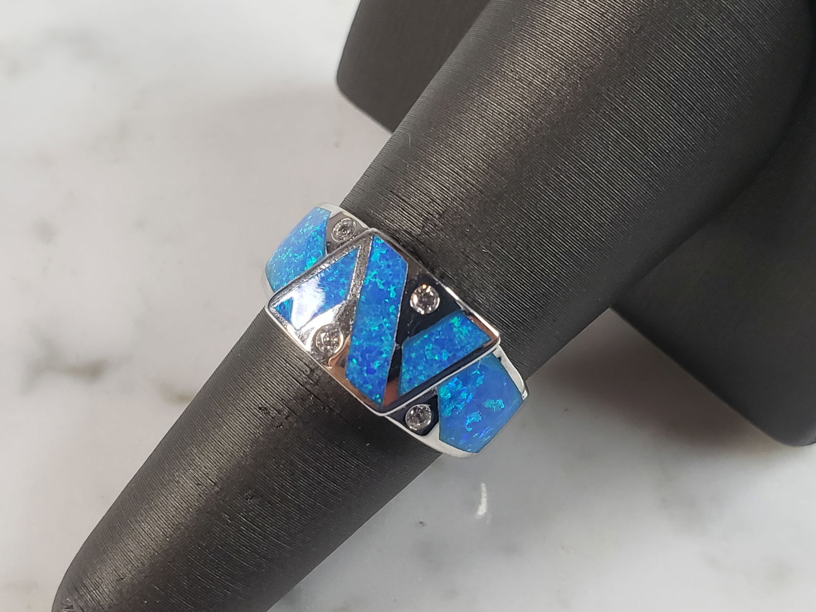 Womens Estate Sterling Silver Modernist Blue Opal & CZ Ring: A WOMENS ESTATE STERLING SILVER MODERNIST BLUE OPAL COLORED RING. THE RING IS A SIZE 7.0, AND WEIGHS 4.8g. WIDTH OF RING MEASURES 3/8". NOT SURE IF STONE IS NATURAL OR MAN MADE. THE RING MAKES A BEAUT
