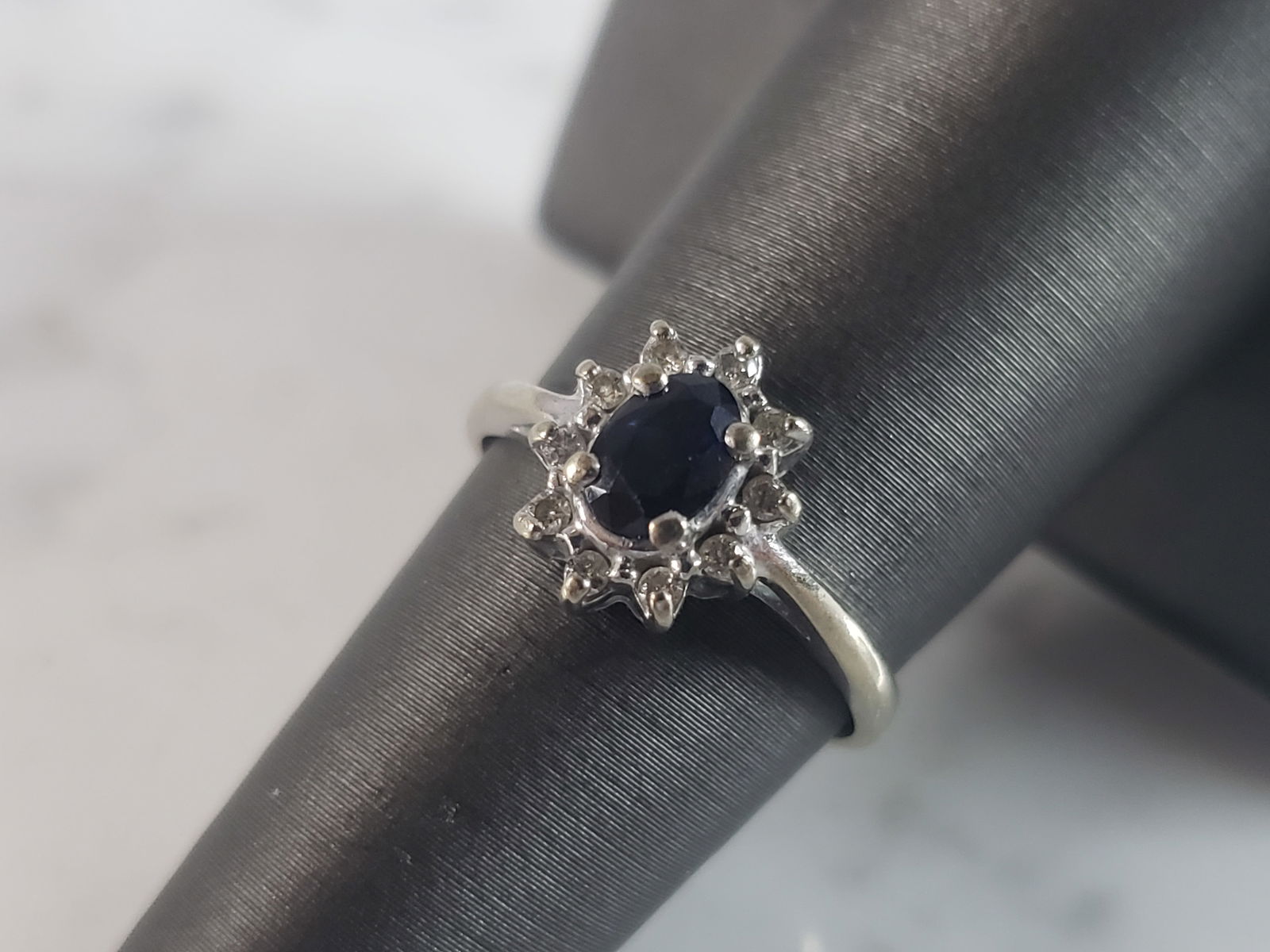 Womens Vintage Estate 10K Gold Sapphire & Diamond Ring: A WOMENS VINTAGE ESTATE 10K GOLD RING WITH TEN .05 ROUND DIAMONDS AND A .20 CT. OVAL DEEP BLUE STONE THAT LOOKS LIKE SAPPHIRE. NOT SURE IF THE CENTER STONE IS REAL OR MANMADE. THE RING WEIGHS 2.3g. SI