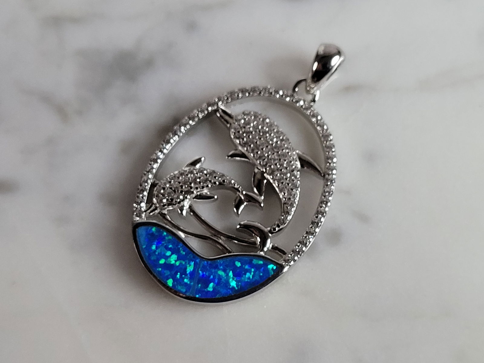 Womens Sterling Silver Blue Opal Dolphin Pendant: A WOMENS STERLING SILVER BLUE OPAL DOLPHIN PENDANT. NOT SURE IF STONES ARE REAL OR MAN MADE. THE PENDANT WEIGHS 4.5g AND MEASURES 1 1/4" LONG BY 7/8" WIDE. MAKES A GREAT GIFT FOR THAT SOMEONE SPECIAL.