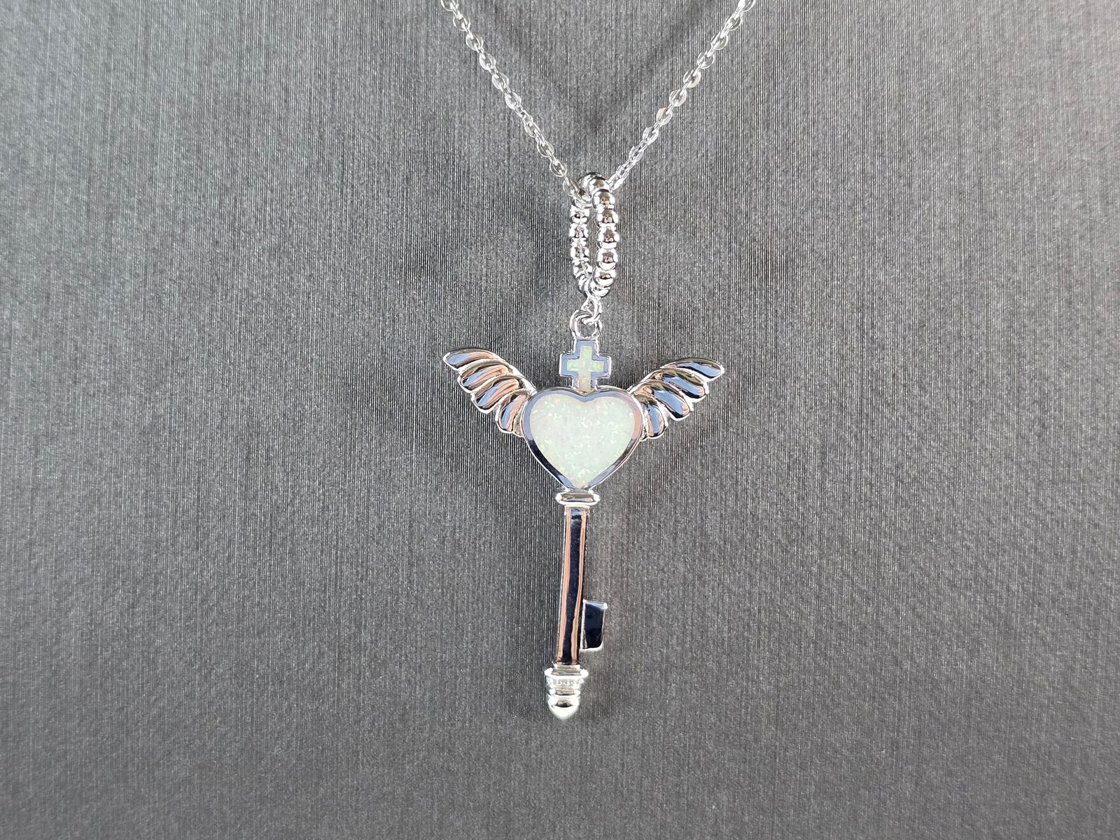 Womens Sterling Silver Opal Winged Cross Heart Pendant Necklace: A WOMENS STERLING SILVER OPAL WINGED CROSS HEART PENDANT. THE PENDANT WITH NECKLACE WEIGHS 5.0g. THE PENDANT MEASURES 1 3/4" LONG BY 1" WIDE, AND THE NECKLACE MEASURES 18" LONG, ADJUSTABLE TO 16" LONG