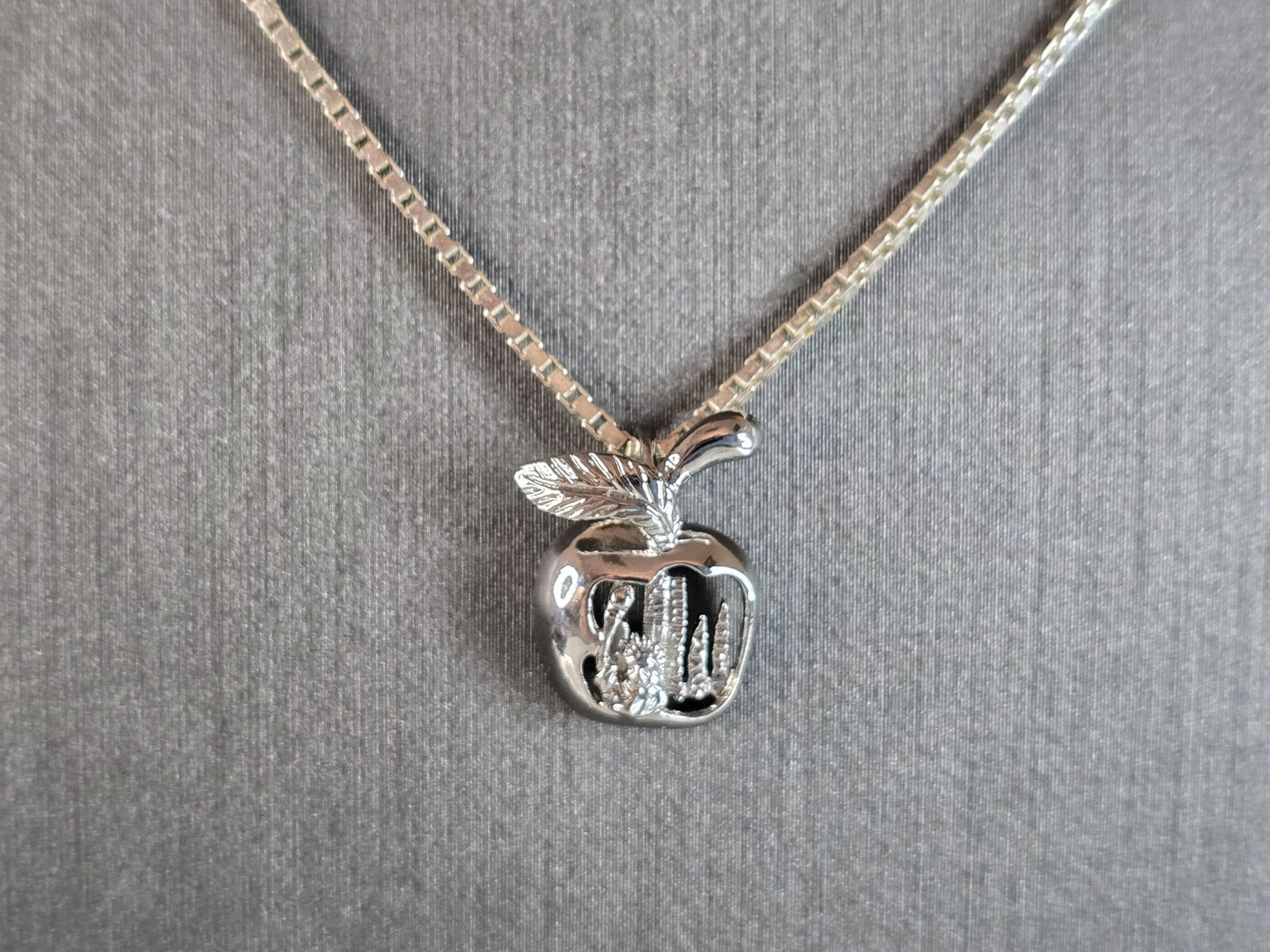 Womens Vintage Estate Sterling Silver Necklace w/ Big Apple NYC Pendant: A WOMENS VINTAGE ESTATE STERLING SILVER NECKLACE WITH A NYC BIG APPLE PENDANT. TOGETHER THEY WEIGH 5.7g. THE NECKLACE MEASURES 20" LONG. THE PENDANT MEASURES 1/2" LONG BY 1/2" WIDE. THIS WOULD MAKE A