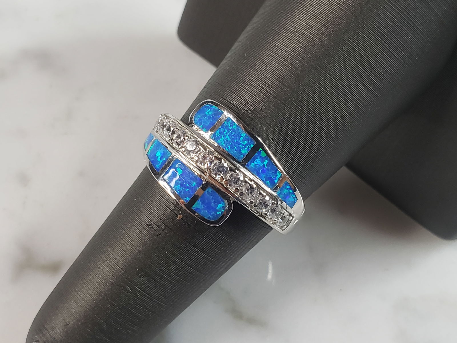Womens Estate Sterling Silver Modernist Blue Opal & CZ Ring: A WOMENS ESTATE STERLING SILVER MODERNIST BLUE OPAL COLORED RING. THE RING IS A SIZE 7.0 AND WEIGHS 4.5g. WIDTH OF RING MEASURES 1/2". NOT SURE IF STONE IS NATURAL OR MAN MADE. THE RING MAKES A BEAUTI