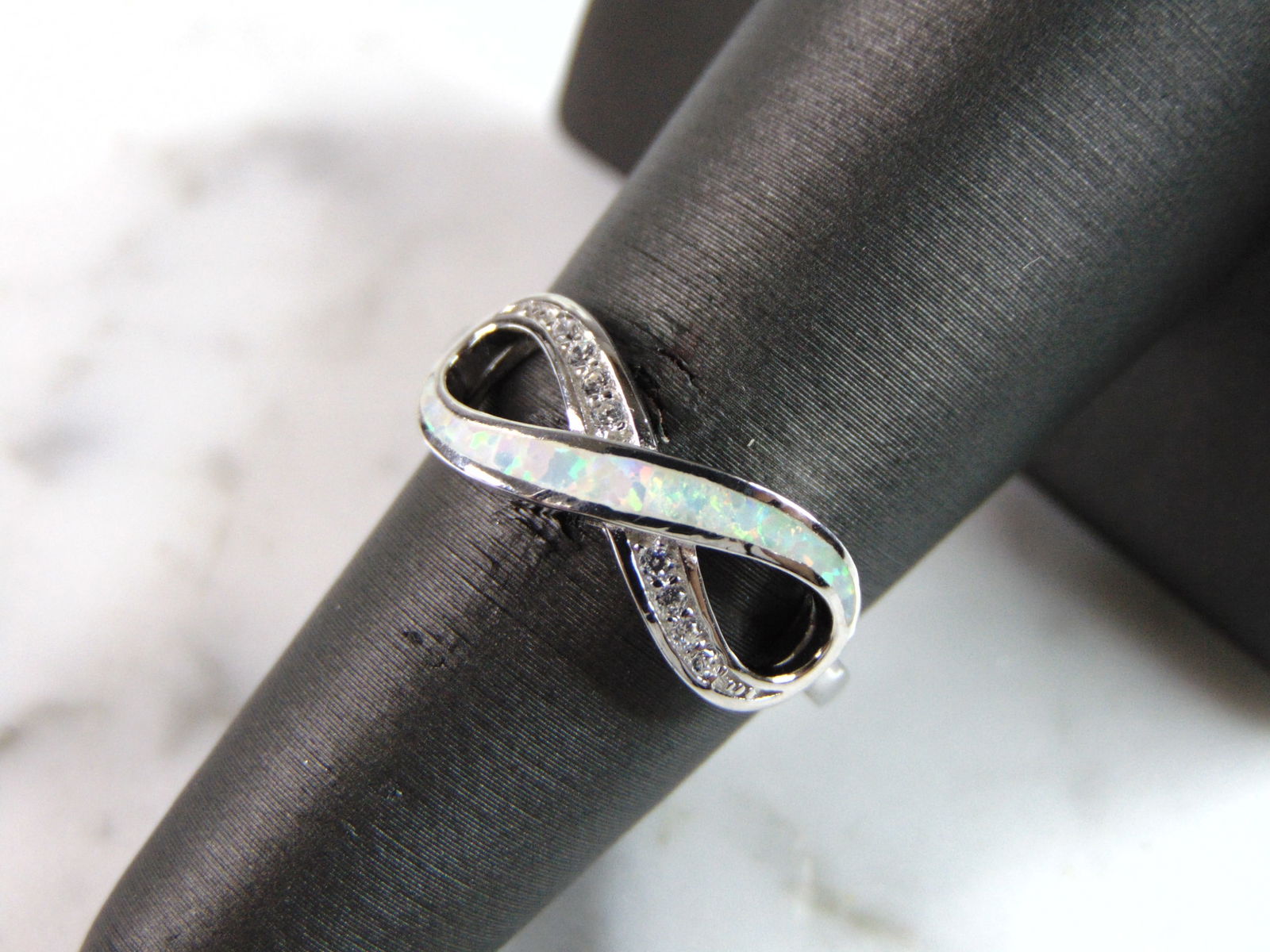 Womens Estate Sterling Silver Modernist Infinity Opal Ring: A WOMENS ESTATE STERLING SILVER MODERNIST INFINITY OPAL COLORED RING. THE RING IS A SIZE 8.0, AND WEIGHS 2.6g. NOT SURE IF STONE IS NATURAL OR MAN MADE. THE RING MAKES A BEAUTIFUL GIFT FOR THAT SOMEON