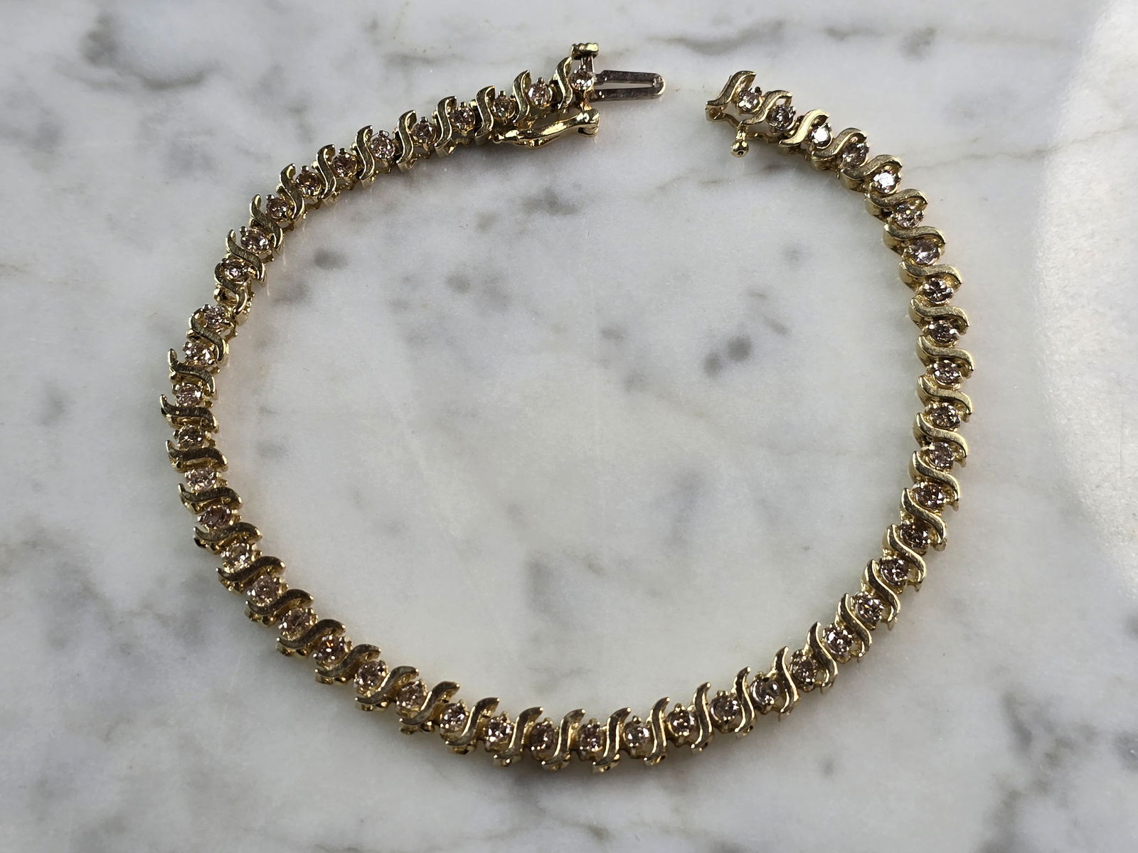 Womens Vintage Estate 14K Gold Diamond Tennis Bracelet: A LOVELY WOMENS VINTAGE ESTATE 14K YELLOW GOLD TENNIS BRACELET WITH ABOUT 1.44cts OF DIAMONDS. THE BRACELET WEIGHS 9.6g AND MEASURES 7 1/2" LONG, BY 1/4" WIDE. ONE OF THE LINKS IS SLIGHTLY BENT AND SH