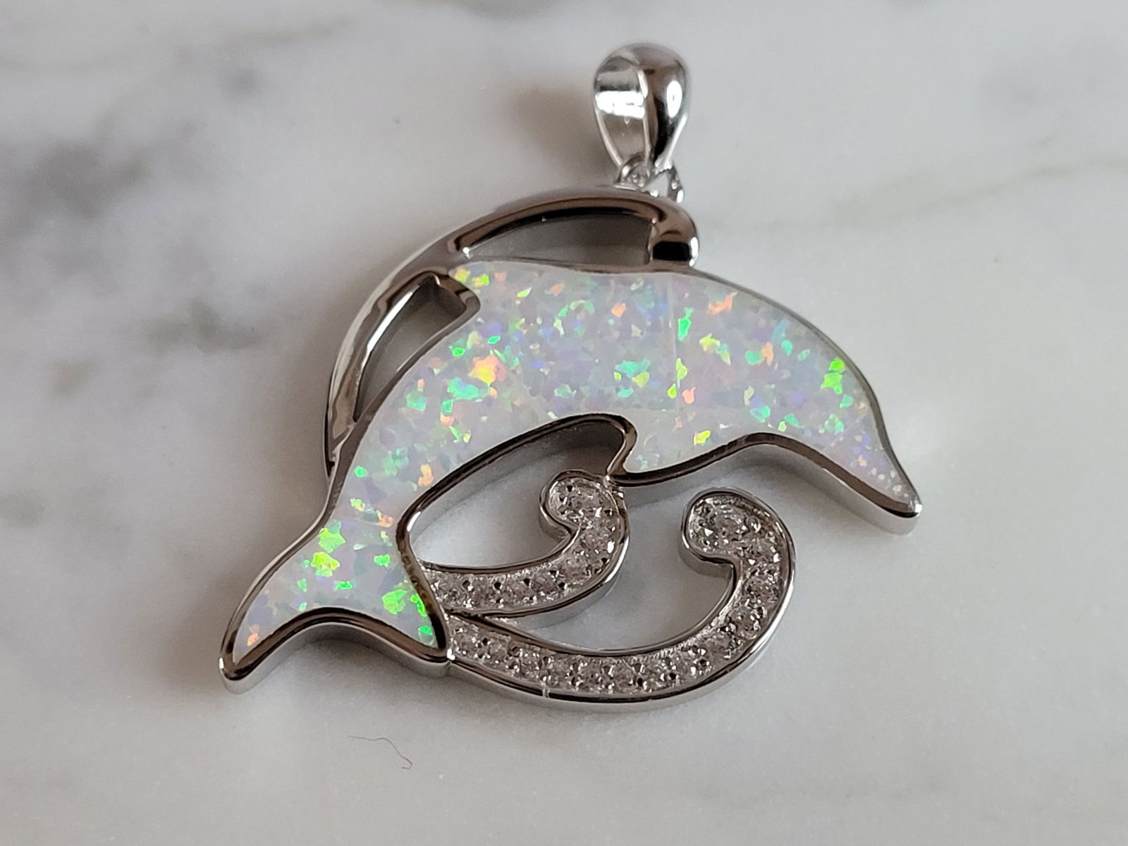 Womens Sterling Silver Opal Dolphin Pendant: A WOMENS STERLING SILVER OPAL DOLPHIN PENDANT. NOT SURE IF STONES ARE REAL OR MAN MADE. THE PENDANT WEIGHS 6.4g AND MEASURES 1 3/8" LONG BY 1" WIDE. MAKES A GREAT GIFT FOR THAT SOMEONE SPECIAL. ANY QU
