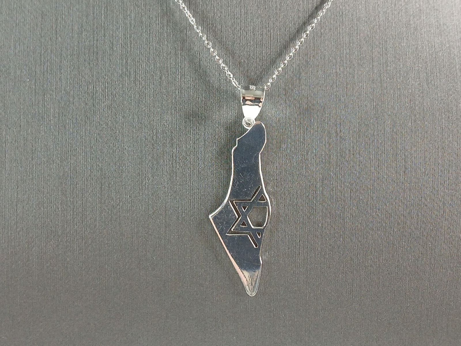 Sterling Silver Jewish Judaica Star of David Israel Pendant Necklace: A STERLING SILVER JUDAICA STAR OF DAVID PENDANT IN THE SHAPE OF ISRAEL. THE PENDANT WITH NECKLACE WEIGHS 4.1g. THE NECKLACE MEASURES 18" LONG AND IS ADJUSTABLE TO 16" LONG. THE PENDANT MEASURES 1 3/4"