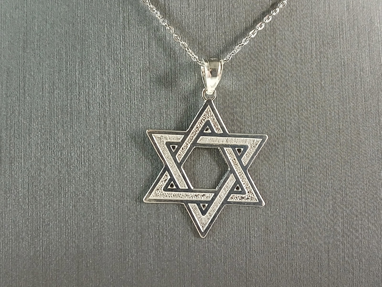 Sterling Silver Jewish Judaica Star of David Pendant Necklace: A STERLING SILVER STAR OF DAVID PENDANT WITH NECKLACE. THE PENDANT WITH NECKLACE WEIGHS 2.6g. THE NECKLACE MEASURES 18" LONG, AND IS ADJUSTABLE TO 16" LONG. THE PENDANT MEASURES 1 1/4" LONG BY 7/8" WI