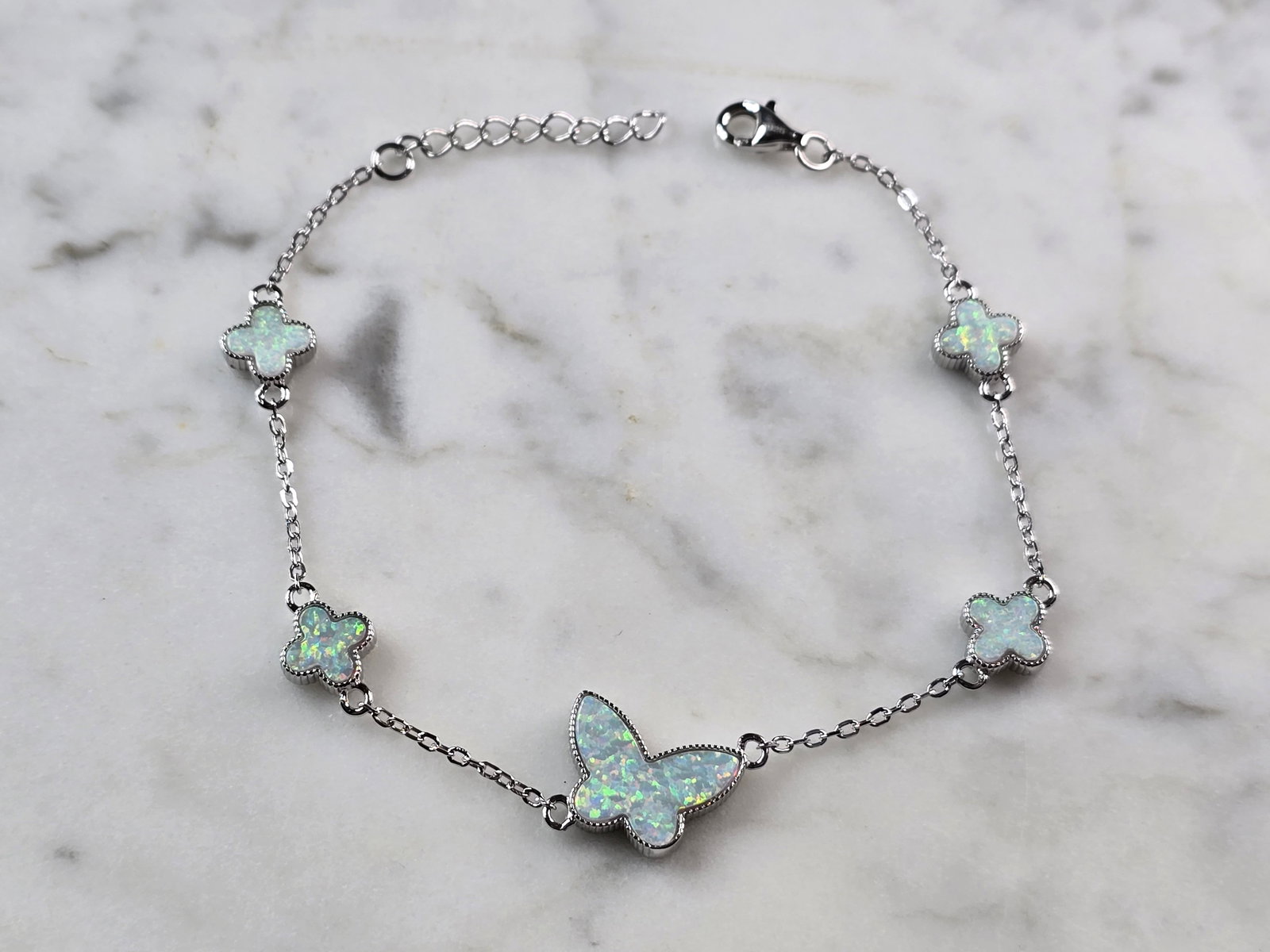 Womens Sterling Silver Opal Butterfly Charm Bracelet: A WOMENS STERLING SILVER MODERNIST OPAL COLORED BUTTERFLY CHARM BRACELET. THE BRACELET WEIGHS 5.3g AND MEASURES 7 3/8" LONG BY 1/2". NOT SURE IF OPAL IS NATURAL OR MAN MADE. ANY QUESTIONS PLEASE DO NO