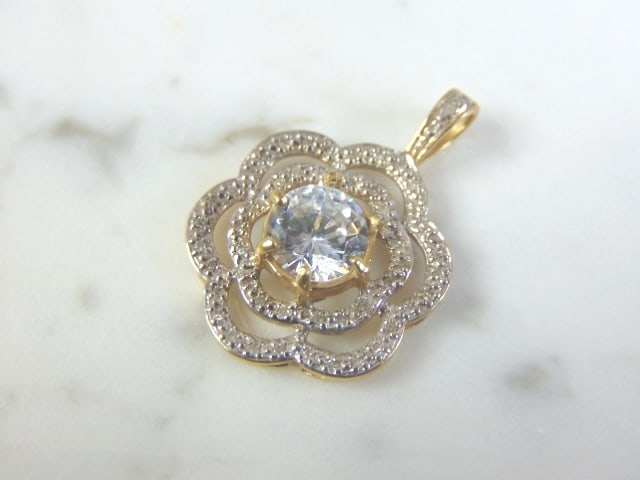 Womens Vintage Estate 10K Gold Diamond Flower Pendant: A WOMENS VINTAGE ESTATE 10K GOLD FLOWER PENDANT WITH DIAMONDS. PENDANT TOTAL CT WEIGHT IS ABOUT .53cts, CENTER STONE IS NOT A DIAMOND. PENDANT WEIGHS 2.5g, AND MEASURES 1 1/8" BY 3/4". WOULD MAKE A LO