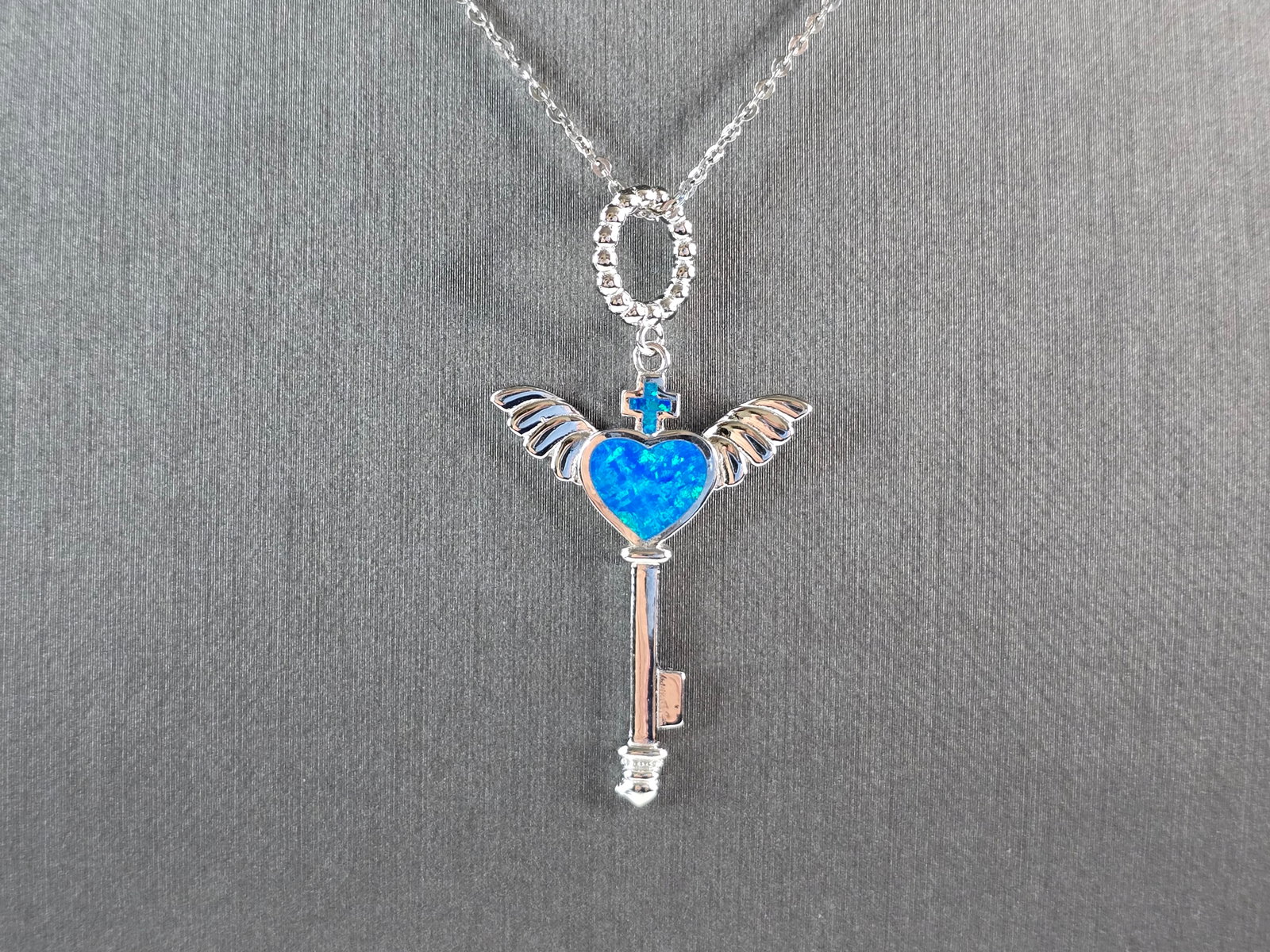 Womens Sterling Silver Blue Opal Winged Cross Heart Pendant Necklace: A WOMENS STERLING SILVER BLUE OPAL WINGED CROSS HEART PENDANT. THE PENDANT WITH NECKLACE WEIGHS 5.0g. THE PENDANT MEASURES 1 3/4" LONG BY 1" WIDE, AND THE NECKLACE MEASURES 18" LONG, ADJUSTABLE TO 16"