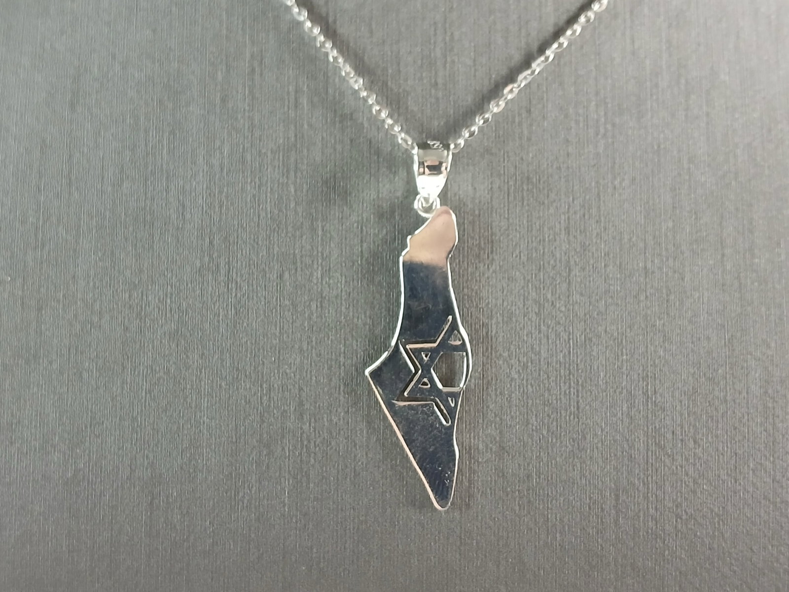 Sterling Silver Jewish Judaica Star of David Israel Pendant Necklace: A STERLING SILVER JUDAICA STAR OF DAVID PENDANT IN THE SHAPE OF ISRAEL. THE PENDANT WITH NECKLACE WEIGHS 3.3g. THE NECKLACE MEASURES 18" LONG AND IS ADJUSTABLE TO 16" LONG. THE PENDANT MEASURES 1 1/2"