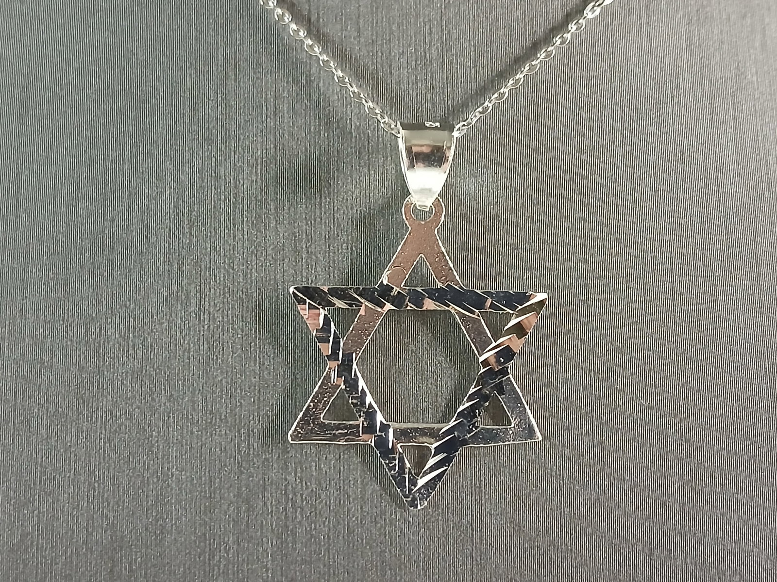 Sterling Silver Jewish Judaica Star of David Pendant Necklace: A STERLING SILVER STAR OF DAVID PENDANT WITH NECKLACE. THE PENDANT WITH NECKLACE WEIGHS 3.5g. THE NECKLACE MEASURES 18" LONG, AND IS ADJUSTABLE TO 16" LONG. THE PENDANT MEASURES 1 3/8" LONG BY 7/8" WI