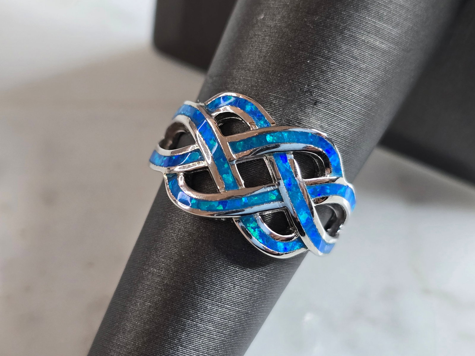 Womens Estate Sterling Silver Eternity Knot Blue Opal Ring: A WOMENS ESTATE STERLING SILVER ETERNITY KNOT BLUE OPAL RING. THE RING IS A SIZE 7.0 AND WEIGHS 5.1g. FACE OF RING MEASURES 1/2" WIDE. THE RING MAKES A BEAUTIFUL GIFT FOR THAT SOMEONE SPECIAL. ANY QUE