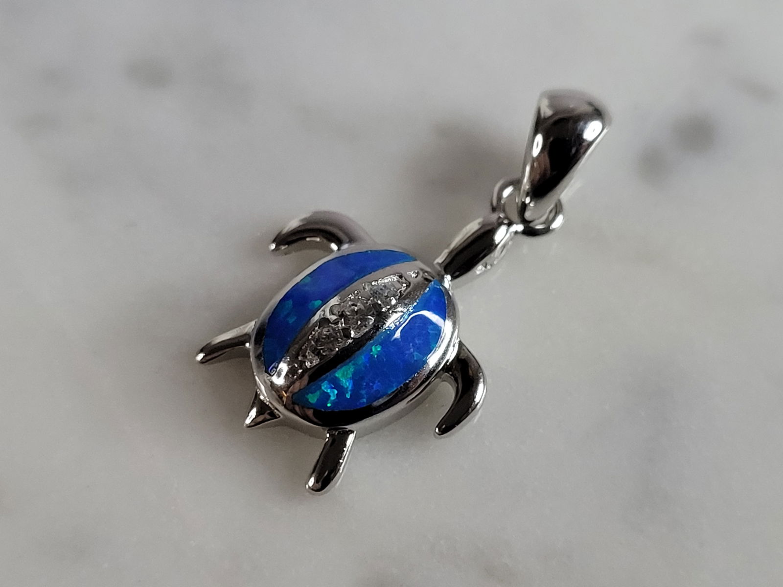 Womens Sterling Silver Blue Opal Sea Turtle Pendant: A WOMENS STERLING SILVER BLUE OPAL SEA TURTLE PENDANT. NOT SURE IF STONES ARE REAL OR MAN MADE. THE PENDANT WEIGHS 2.1g AND MEASURES 7/8" LONG BY 1/2" WIDE. MAKES A GREAT GIFT FOR THAT SOMEONE SPECIAL