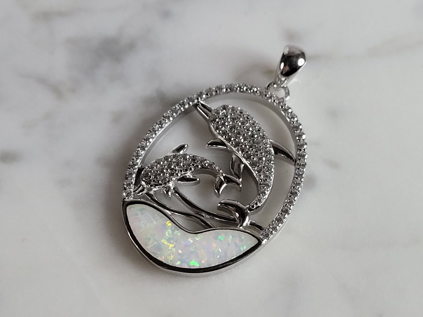 Womens Sterling Silver Opal Dolphin Pendant: A WOMENS STERLING SILVER OPAL DOLPHIN PENDANT. NOT SURE IF STONES ARE REAL OR MAN MADE. THE PENDANT WEIGHS 5.2g AND MEASURES 1 1/4" LONG BY 7/8" WIDE. MAKES A GREAT GIFT FOR THAT SOMEONE SPECIAL. ANY