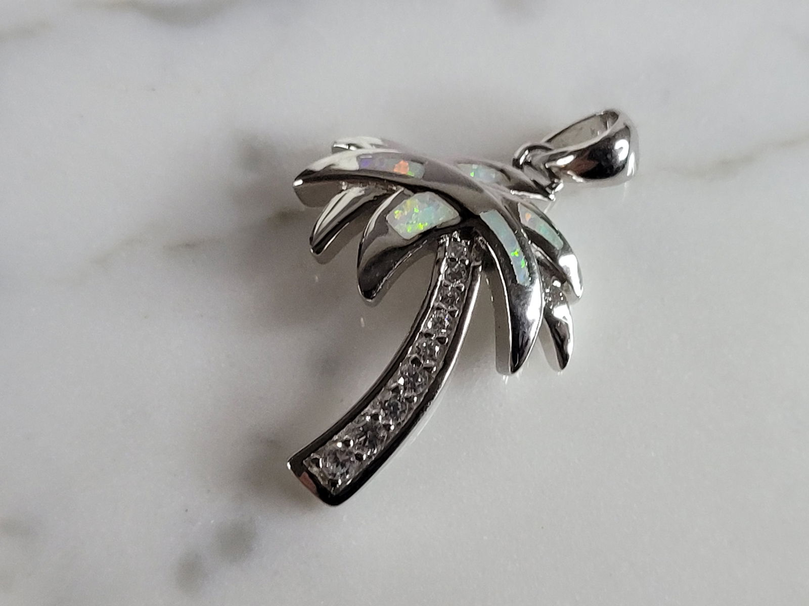 Womens Sterling Silver Opal Beach Palm Tree Pendant: A WOMENS STERLING SILVER OPAL PALM TREE PENDANT. NOT SURE IF STONES ARE REAL OR MAN MADE. THE PENDANT WEIGHS 3.3g AND MEASURES 1" LONG BY 5/8" WIDE. MAKES A GREAT GIFT FOR THAT SOMEONE SPECIAL. ANY QU