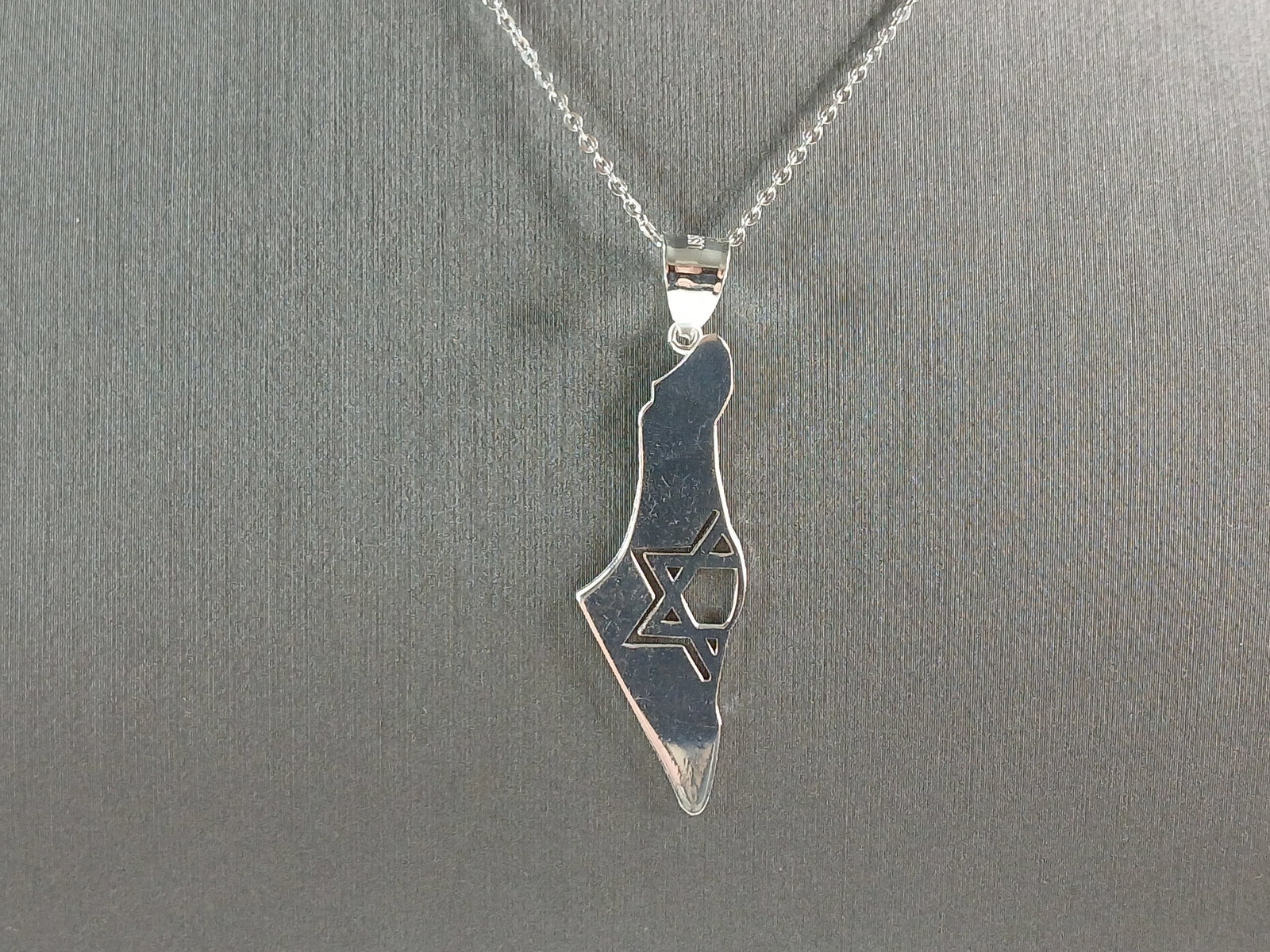 Sterling Silver Jewish Judaica Star of David Israel Pendant Necklace: A STERLING SILVER JUDAICA STAR OF DAVID PENDANT IN THE SHAPE OF ISRAEL. THE PENDANT WITH NECKLACE WEIGHS 4.1g. THE NECKLACE MEASURES 18" LONG AND IS ADJUSTABLE TO 16" LONG. THE PENDANT MEASURES 1 3/4"