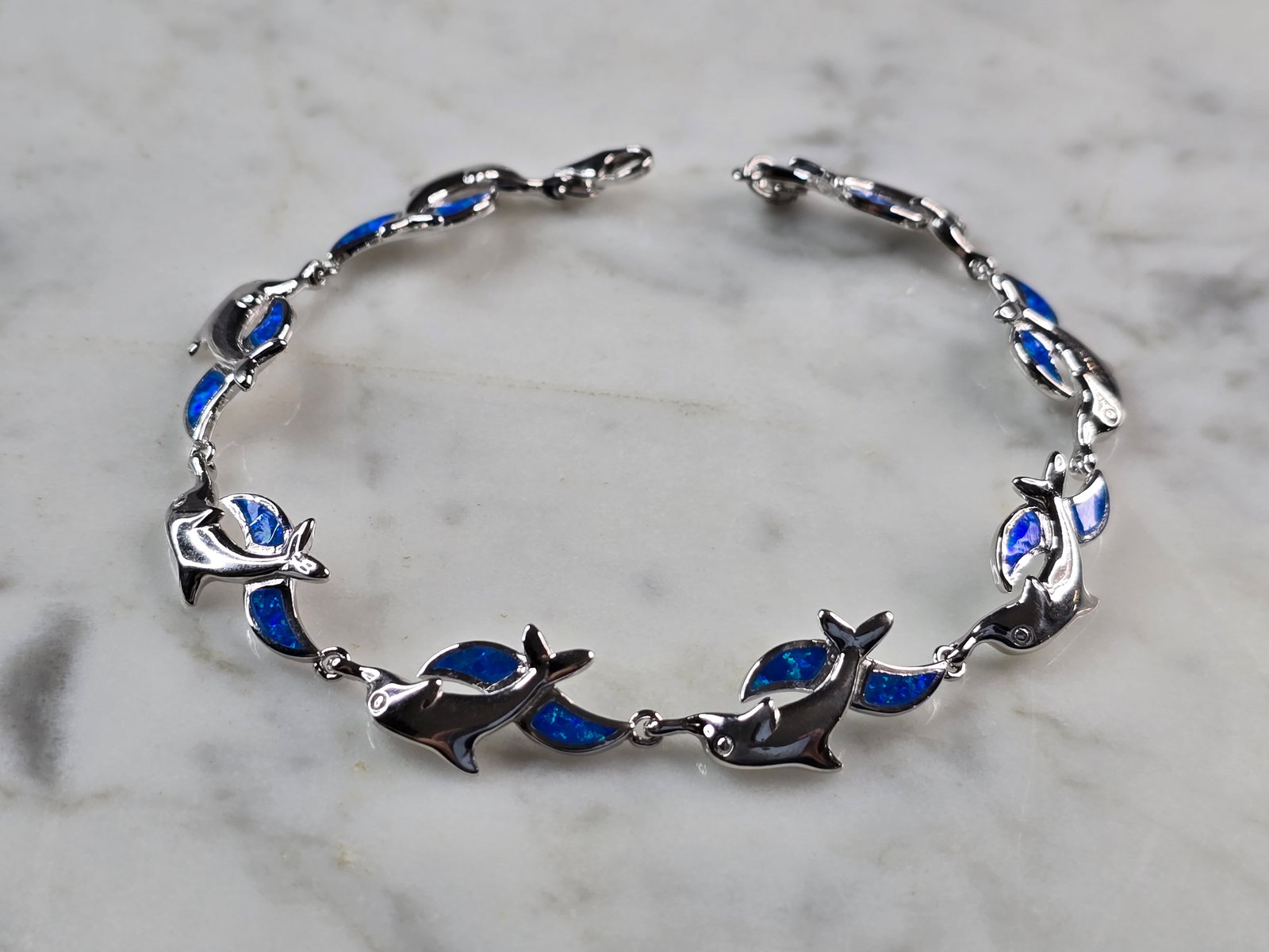 Womens Sterling Silver Opal Dolphin Bracelet: A WOMENS STERLING SILVER MODERNIST OPAL COLORED DOLPHIN BRACELET. THE BRACELET WEIGHS 12.1g AND MEASURES 7 7/8" LONG BY 1/2" WIDE. NOT SURE IF OPAL IS NATURAL OR MAN MADE. ANY QUESTIONS PLEASE DO