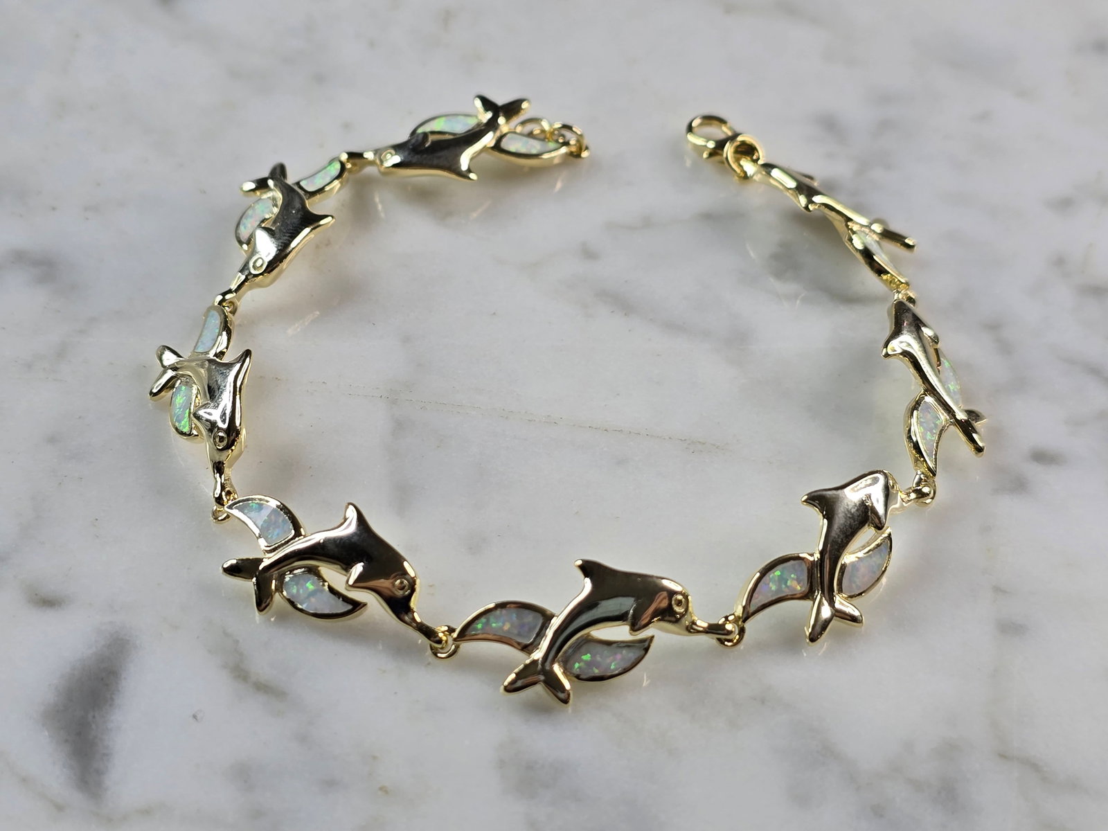 Womens Sterling Silver Gold Tone Opal Dolphin Bracelet: A WOMENS STERLING SILVER GOLD TONE MODERNIST OPAL COLORED DOLPHIN BRACELET. THE BRACELET WEIGHS 12.3g AND MEASURES 7 1/2" LONG BY 1/2" WIDE. NOT SURE IF OPAL IS NATURAL OR MAN MADE. ANY QUESTIONS
