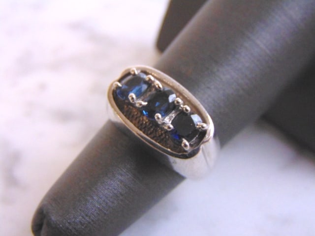 Womens Sterling Silver Ring w/ Sapphire Colored Stones: A WOMENS STERLING SILVER RING WITH A SAPPHIRE COLORED STONES. NOT SURE IF THE STONES ARE NATURAL OR MAN MADE. THE RING WEIGHS 6.9g. THE SIZE OF THE RING IS A 6.0. ANY QUESTIONS PLEASE DO NOT HESITATE