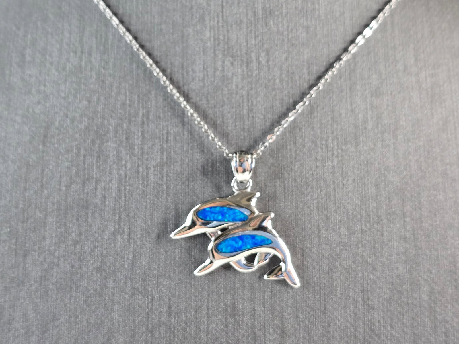 Womens Sterling Silver Blue Opal Dolphin Pendant Necklace: A WOMENS STERLING SILVER BLUE OPAL DOLPHIN PENDANT. THE PENDANT WITH NECKLACE WEIGHS 4.7g. THE PENDANT MEASURES 1" LONG BY 1" WIDE, AND THE NECKLACE MEASURES 18" LONG. NOT SURE IF STONES ARE REAL OR M