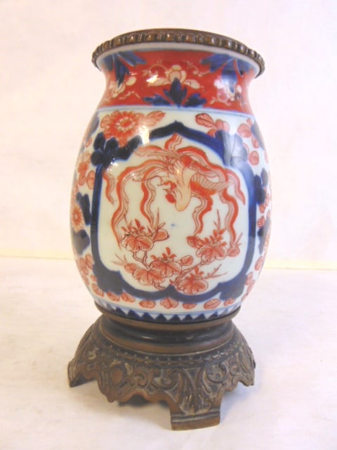 ANTIQUE JAPANESE IMARI PORCELAIN VASE URN: A DECORATIVE ANTIQUE JAPANESE IMARI PORCELAIN VASE/URN. THE VASE MEASURES ABOUT 8" TALL BY 5" WIDE. CONDITION LOOKS GOOD FOR ITS AGE, HOWEVER THE BASE IT SITS ON IS A LITTLE BENT. DOES NOT AFFECT THE