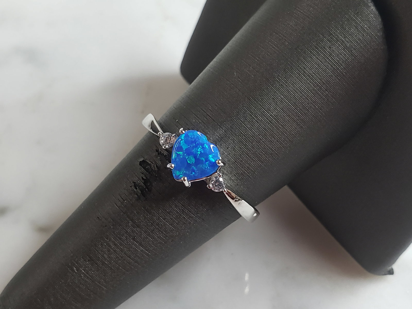 Womens Sterling Silver Modernist Blue Opal Heart Ring: A WOMENS STERLING SILVER MODERNIST OPAL COLORED HEART RING. THE RING IS A SIZE 7.25 AND WEIGHS 1.9g. WIDTH OF RING MEASURES 1/4". NOT SURE IF STONE IS NATURAL OR MAN MADE. THE RING MAKES A BEAUTIFUL G